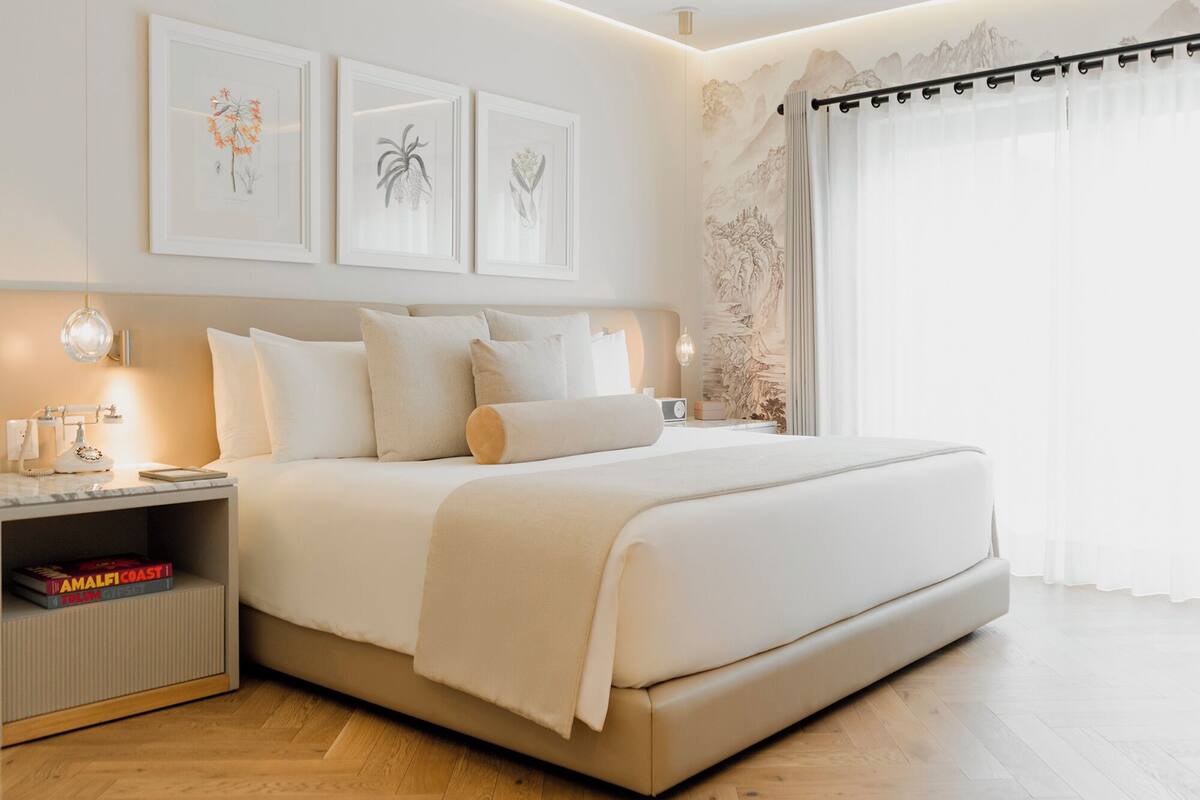 Een moderne slaapkamer met een groot bed, nachtkastjes en kunst aan de muur.