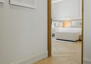 Ein Hotelzimmer mit Holzboden, einem Bett mit weißer Bettwäsche und einem Nachttisch mit einer Lampe.