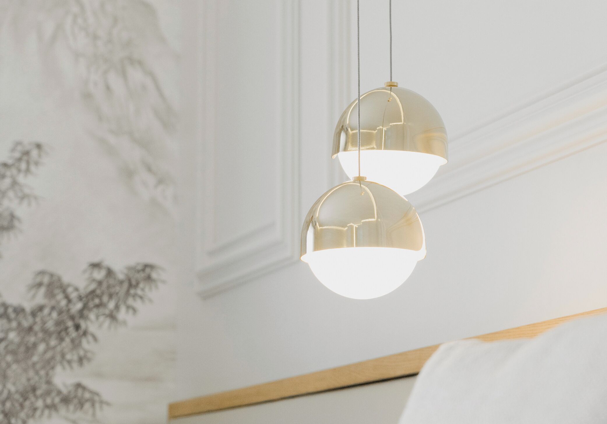 A room with a bed, a wall with a decorative pattern, and two pendant lights.