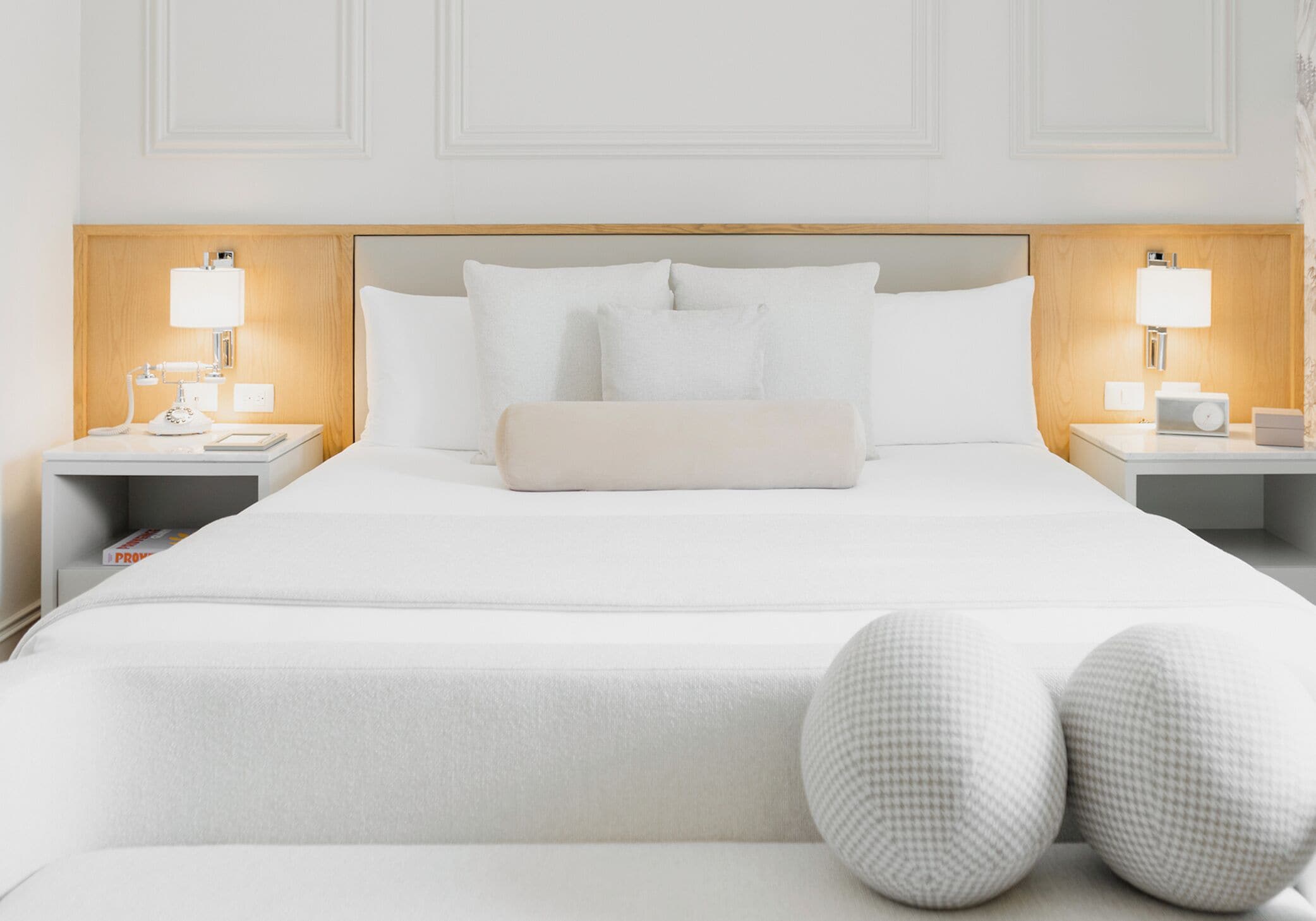 A hotel room with a large bed, two bedside tables with lamps, and a wooden headboard.
