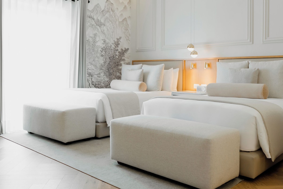 Un dormitorio moderno con una cama grande, dos camas más pequeñas y un área de descanso.