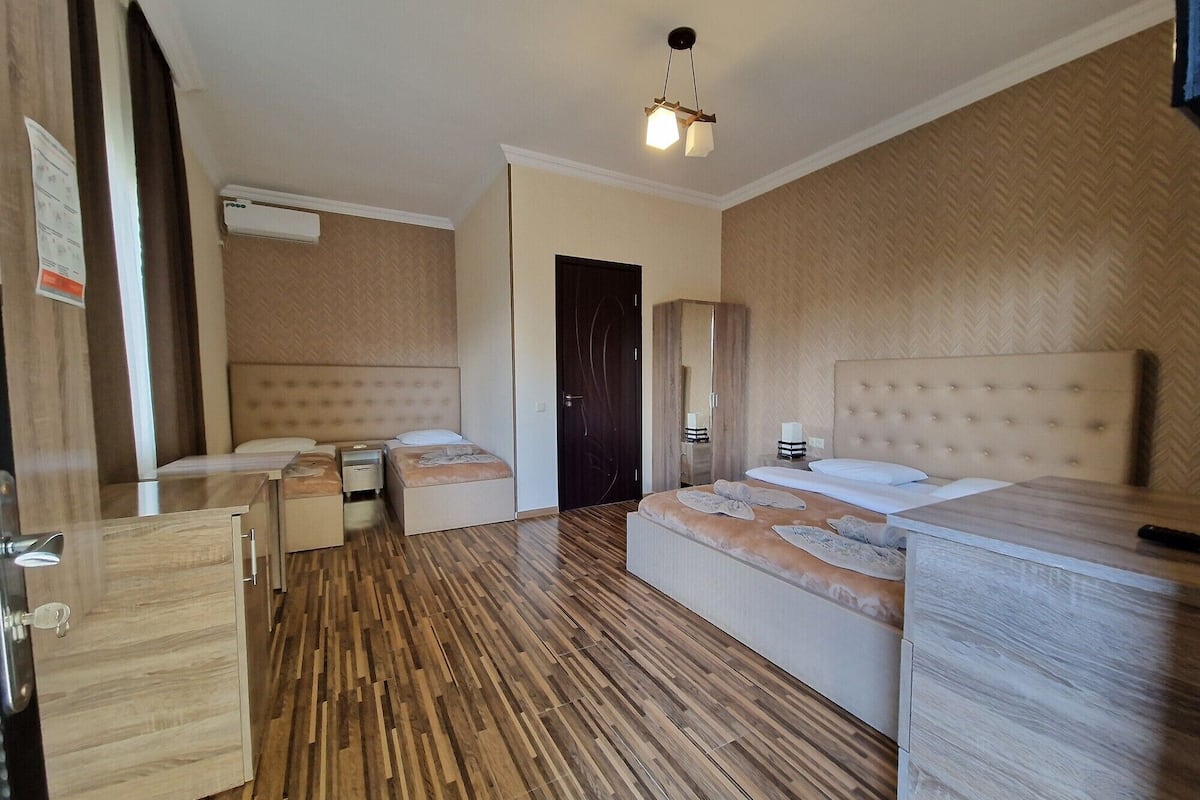 Ein Hotelzimmer mit zwei Betten, einem Kleiderschrank, einem Schreibtisch und einem Spiegel.