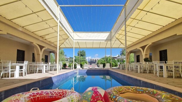 A pool area with a clear view of the sky, surrounded by white tables and chairs. - Hotel Oasis Villa (Tsqaltubo)
