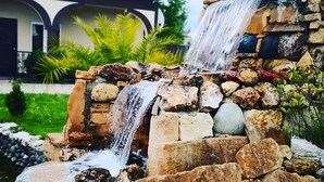A waterfall feature with multiple tiers of rocks and water cascading down. - Hotel Oasis Villa (Tsqaltubo)