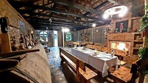 A rustic dining area with a long table set for a meal, benches, and a fireplace. - Hotel Oasis Villa (Tsqaltubo)