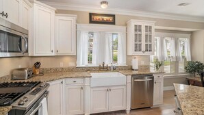 A kitchen with white cabinets, a stainless steel dishwasher, a granite countertop, and a microwave. - Family-Friendly 3BR Condo Grand Haven 27 (Grand Haven)