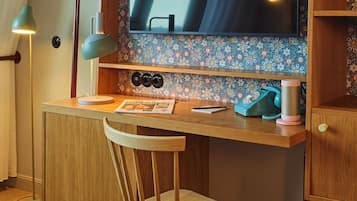 Un escritorio de madera con un televisor de pantalla plana grande, una silla y un teléfono.