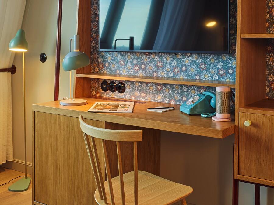 Un escritorio de madera con un televisor de pantalla plana grande, una silla y un teléfono.