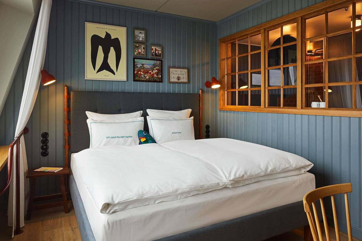 A neatly made bed with white linens, a wooden headboard, and a bedside table with a lamp.