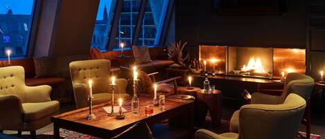 A cozy lounge area with leather sofas, a wooden coffee table, and a fireplace.