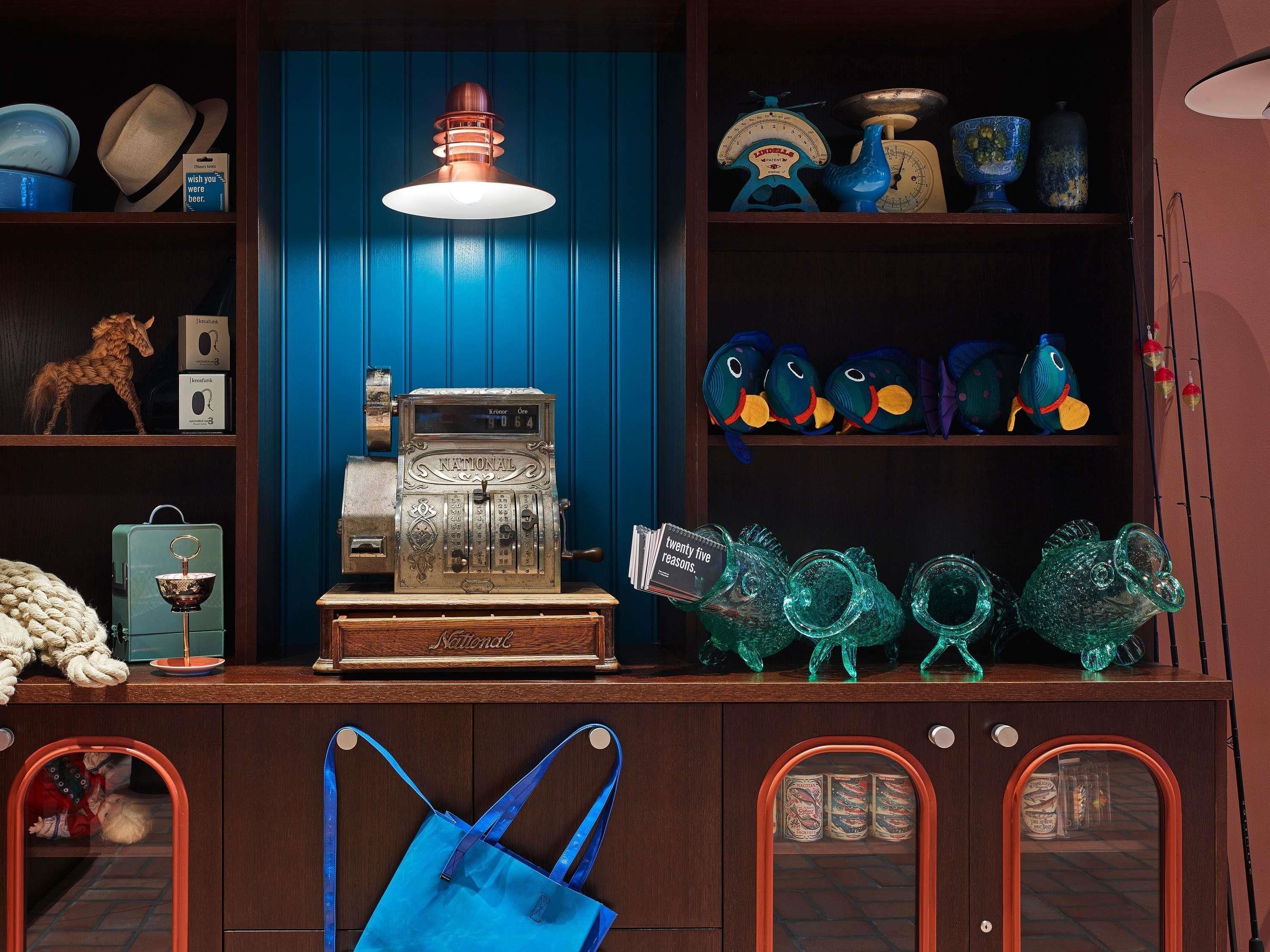 Une pièce au style rétro, avec un mur bleu, une balance ancienne, une caisse enregistreuse et des objets décoratifs.