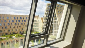 Ein modernes Gebäude mit großem Fenster, Blick auf einen Innenhof und einer Reflexion der Fassade.