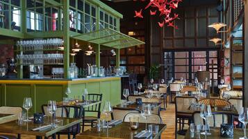 Un interior de restaurante con zona de bar, mesas y sillas para comer.