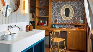 A bathroom with a white sink, two bottles of soap, a toothbrush, and a mirror.