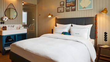 Een netjes ingerichte hotelkamer met een bed, een kaptafel met spiegel en een tafeltje met lamp.