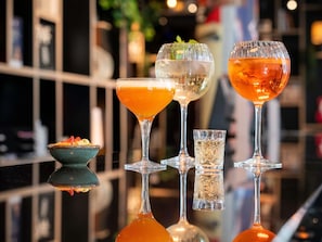 Una zona de bar con distintos vasos de bebidas y un tazón pequeño de comida.