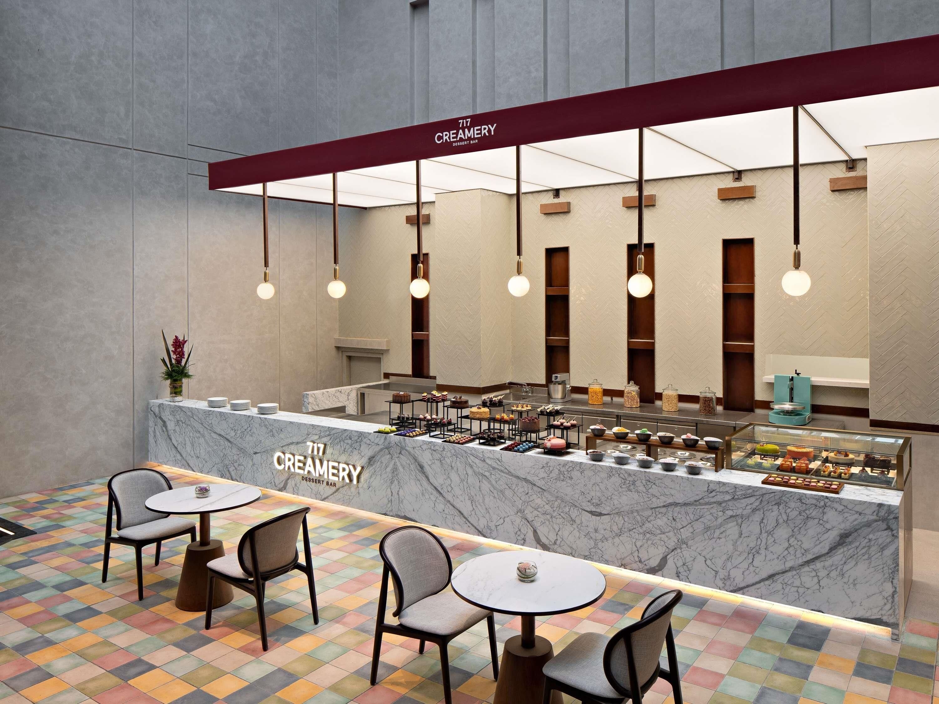 A dessert bar with marble counter, hanging lights, and a colorful tiled floor.