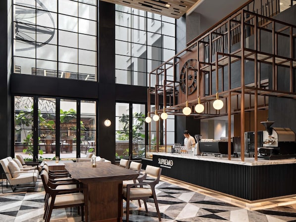 A modern bar area with a wooden counter, seating, and large windows.