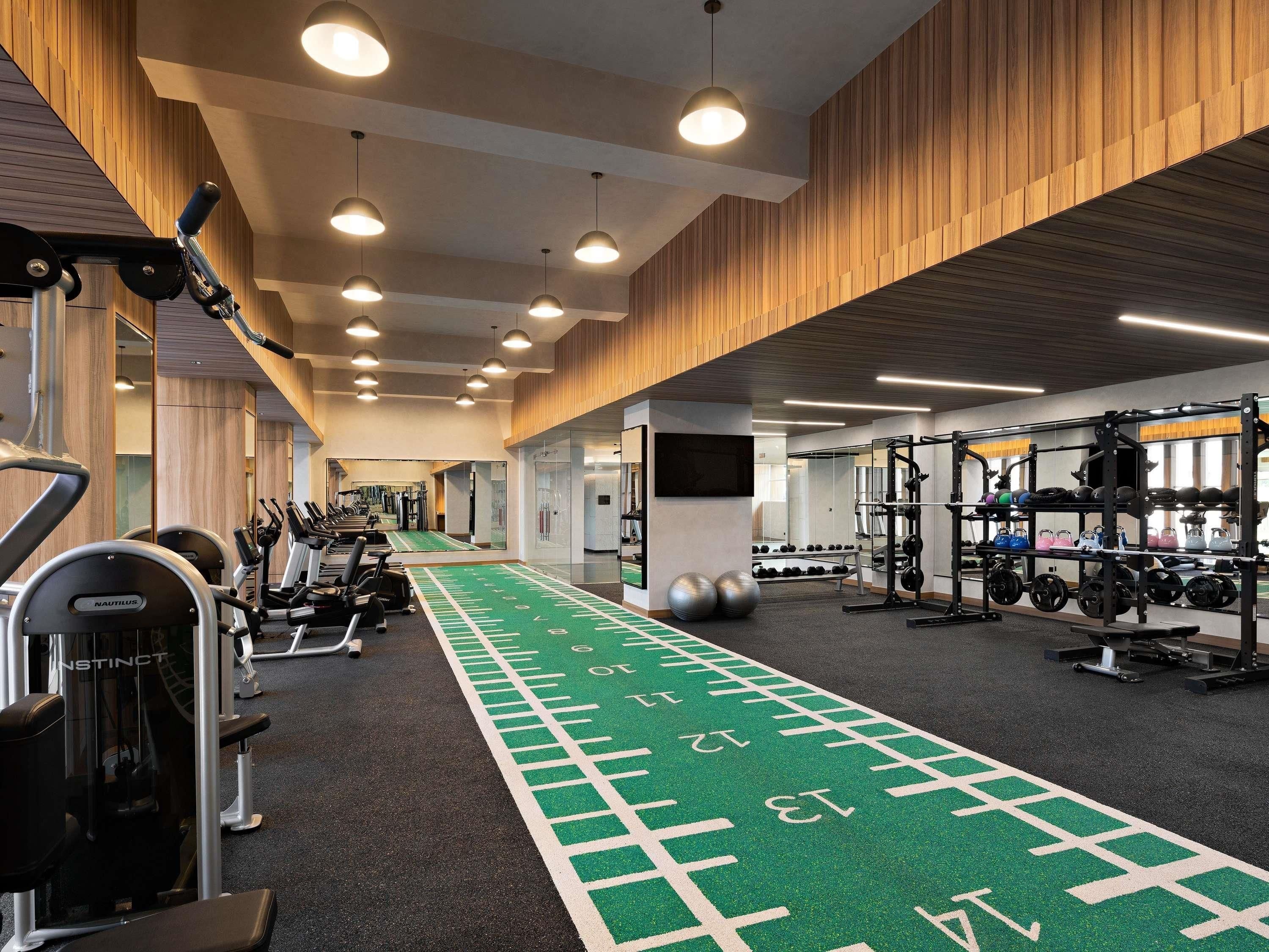 A gym with treadmills, weight machines, and a green running track.