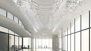 A modern interior with a curved ceiling, large windows, and a reflective floor. - Mövenpick Hotel Jakarta City Centre (Jakarta)