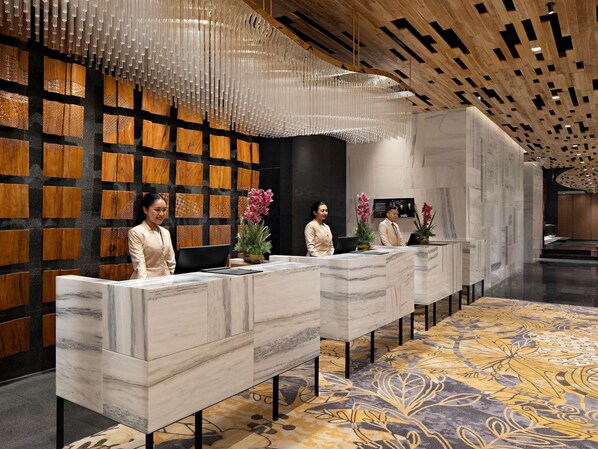A reception area with marble counters, wooden wall panels, and a patterned carpet.