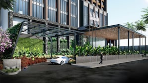A modern building with a covered entrance, large windows, and lush greenery. - Mövenpick Hotel Jakarta City Centre (Jakarta)