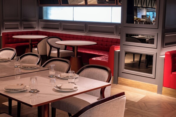 Un restaurante con asientos tapizados en rojo, mesas redondas y una decoración de diseño moderno.