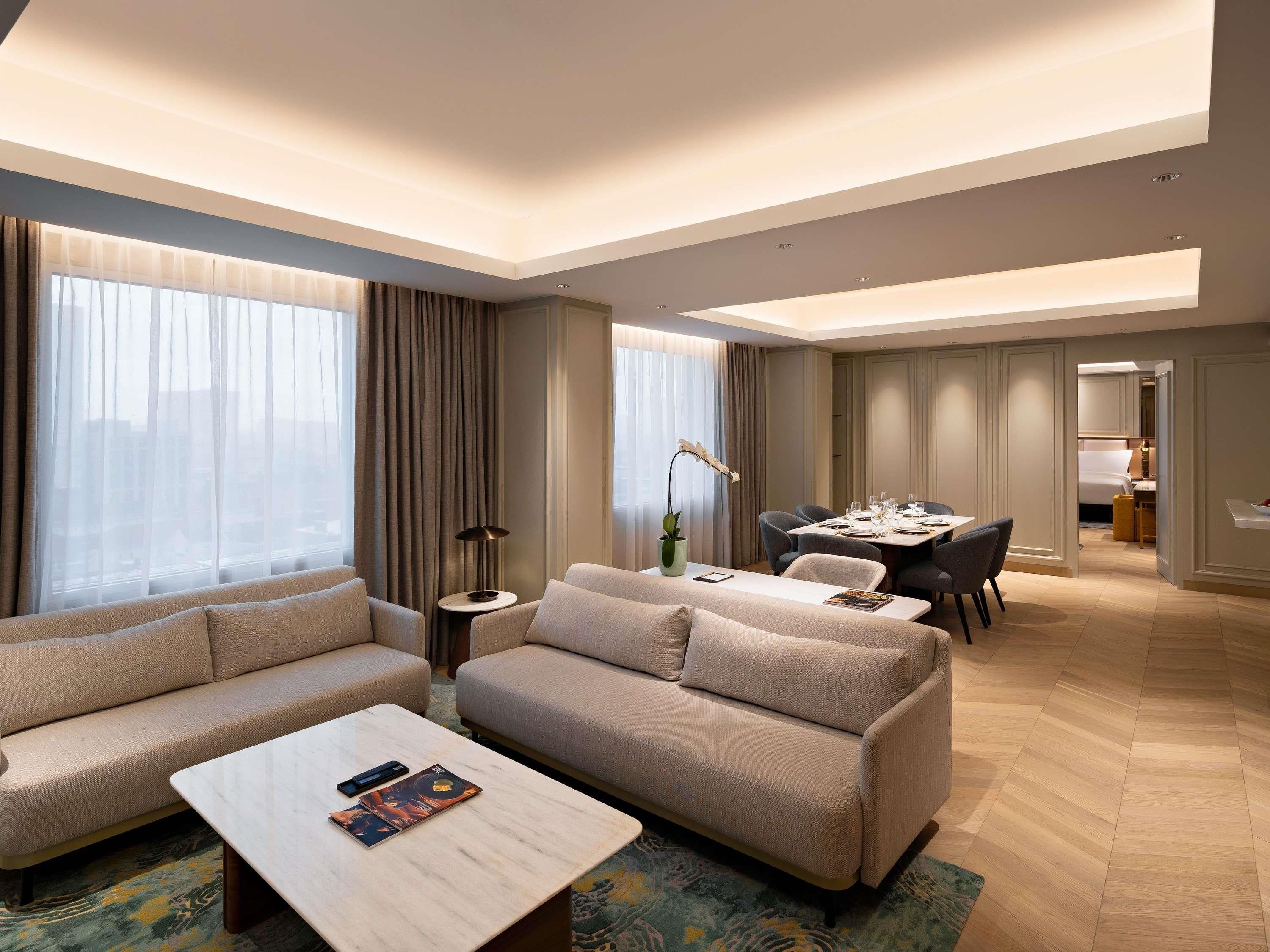 Une chambre d’hôtel moderne équipée d’un canapé, d’une table à manger et d’une petite table d’appoint.