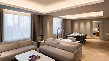 A modern hotel room with a sofa, a dining table, and a small side table.