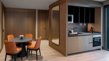 A modern kitchen with a central island, wooden cabinetry, and a dining area with orange chairs and a round table.
