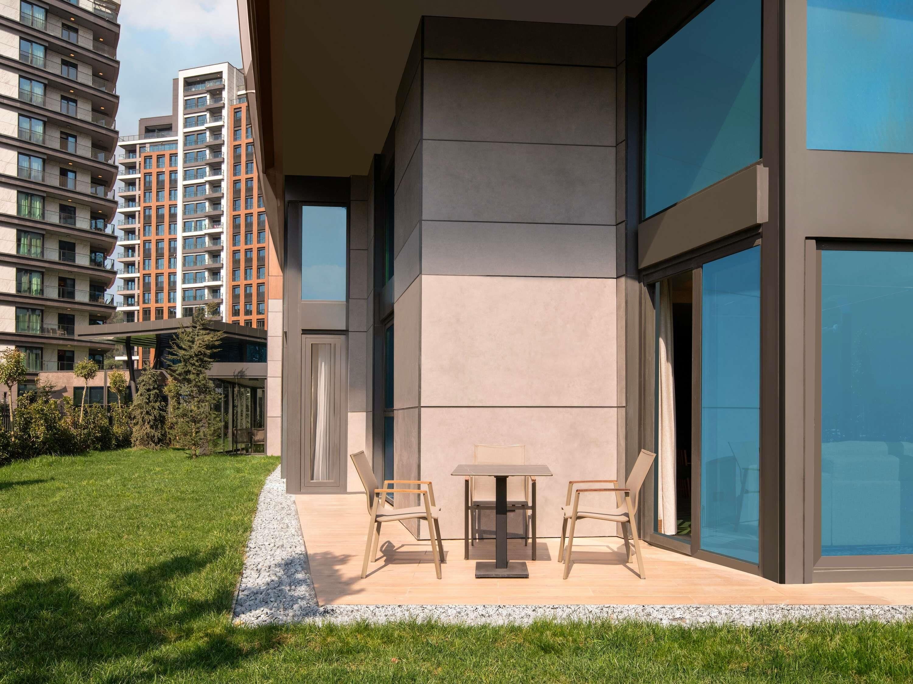 Un edificio moderno con amplios ventanales, techo plano y un patio amoblado al aire libre.