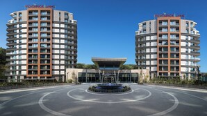 A modern apartment building with balconies, a central fountain, and a clear sky. - Mövenpick Living Istanbul Saklivadi (Istanbul)