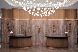 Reception area with two desks, a chandelier, and wooden panel walls.