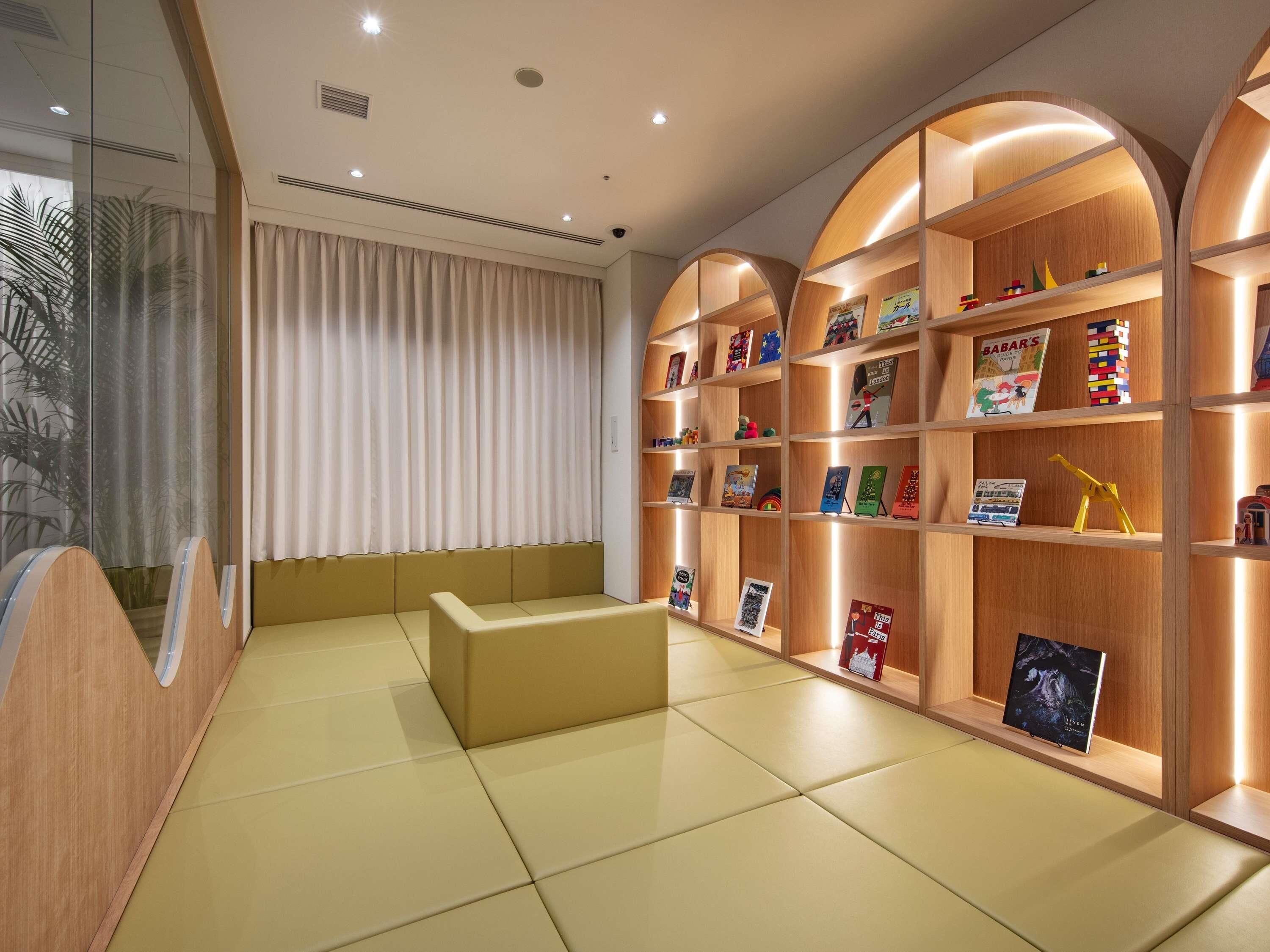 A reading area with a sofa, bookshelves, and a large window with curtains.
