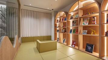 A reading area with a sofa, bookshelves, and a large window with curtains.