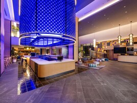 Un lobby moderno con un mostrador de recepción central, zonas de estar y un techo distintivo con estampado azul.