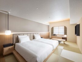 Quarto de hotel moderno com uma cama grande, mesas de cabeceira, um espelho e uma TV de tela plana.