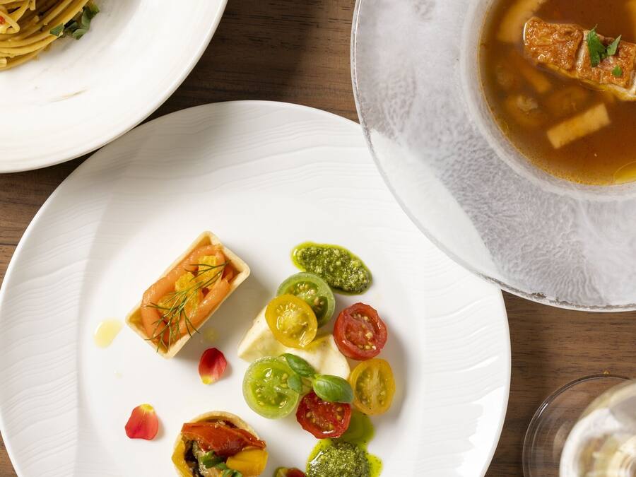 A dining table with plates of food, including pasta, salmon, and various vegetables.