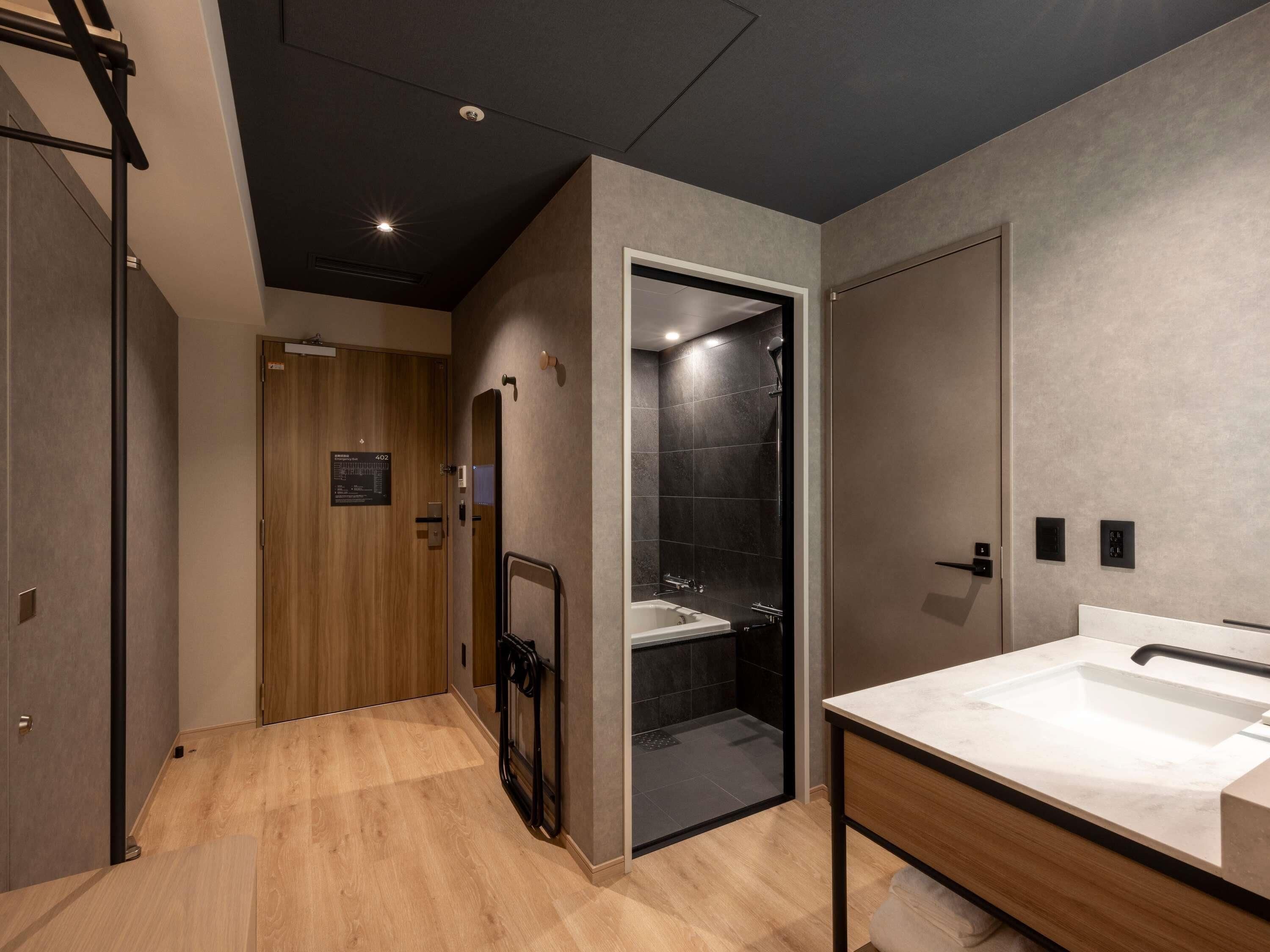 Un baño moderno con ducha, lavamanos y puerta de madera.