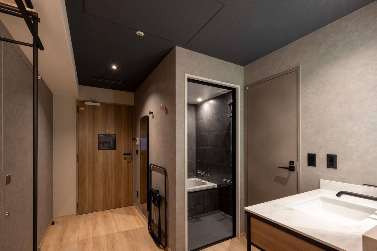 A modern bathroom with a glass-enclosed shower, a wooden door, and a white sink.