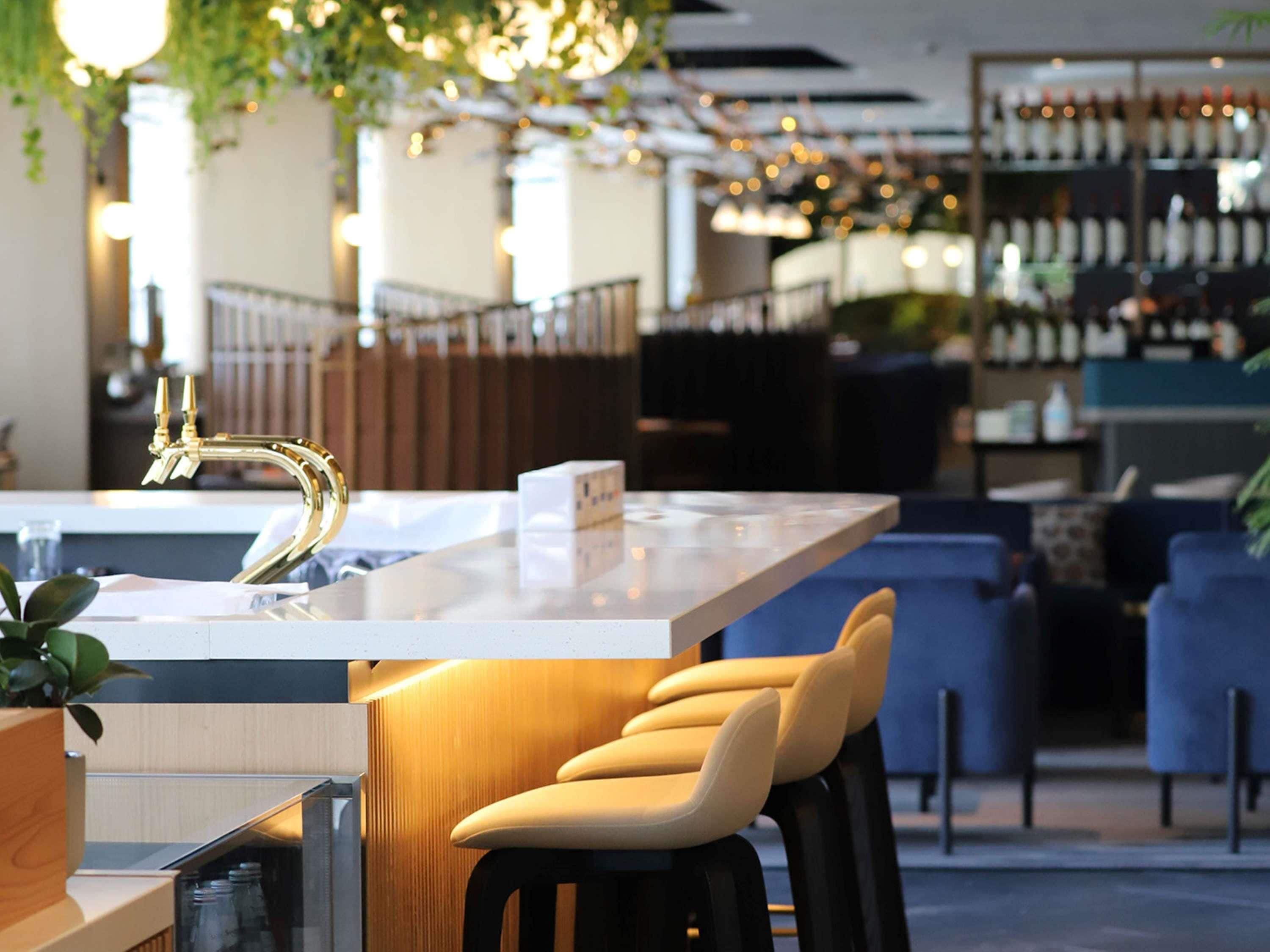 A bar area with a modern bar counter, stools, and a wine rack in the background.