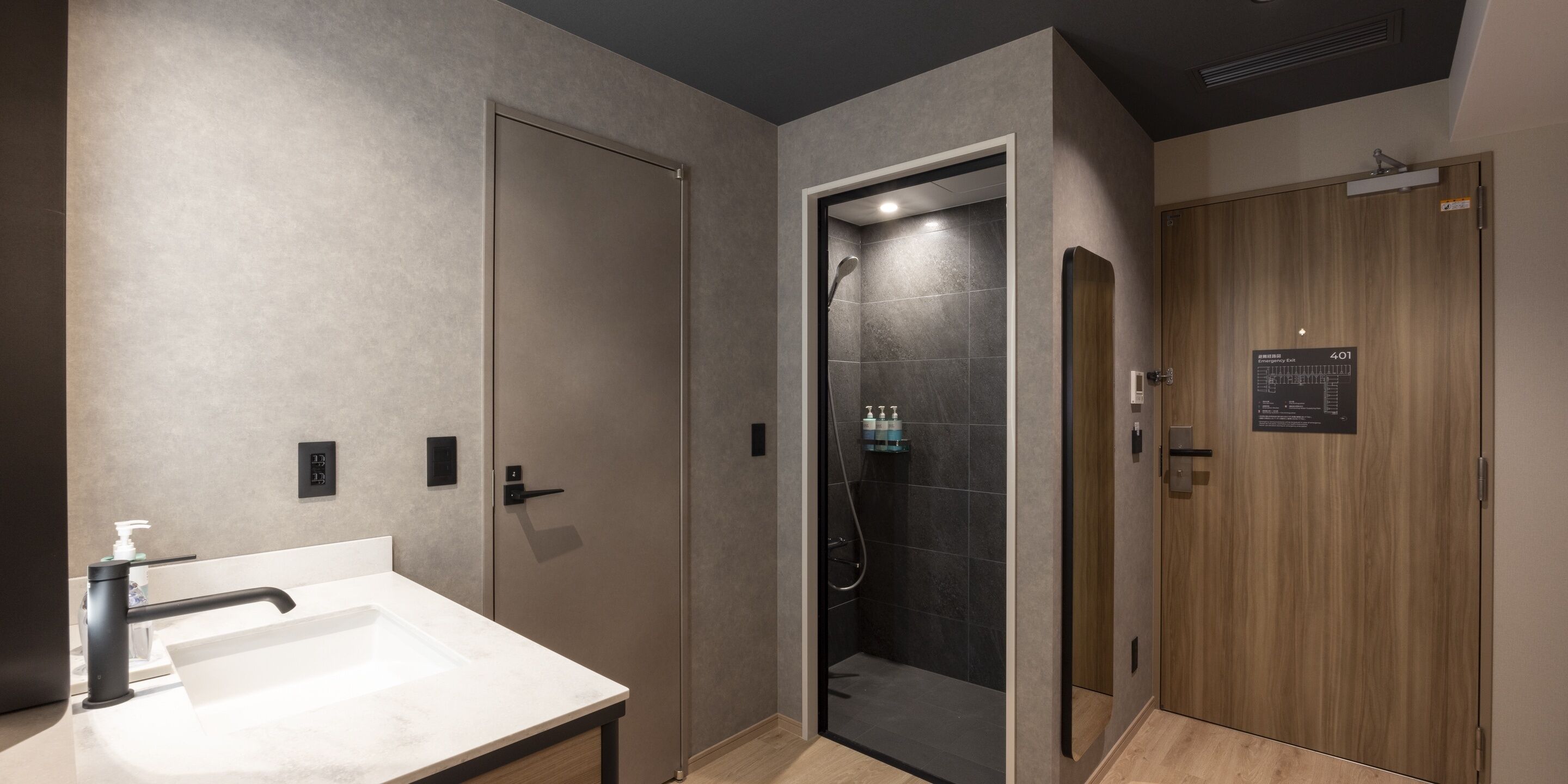 Ein modernes Badezimmer mit einem Waschbecken, einer Dusche und einer Holztür.