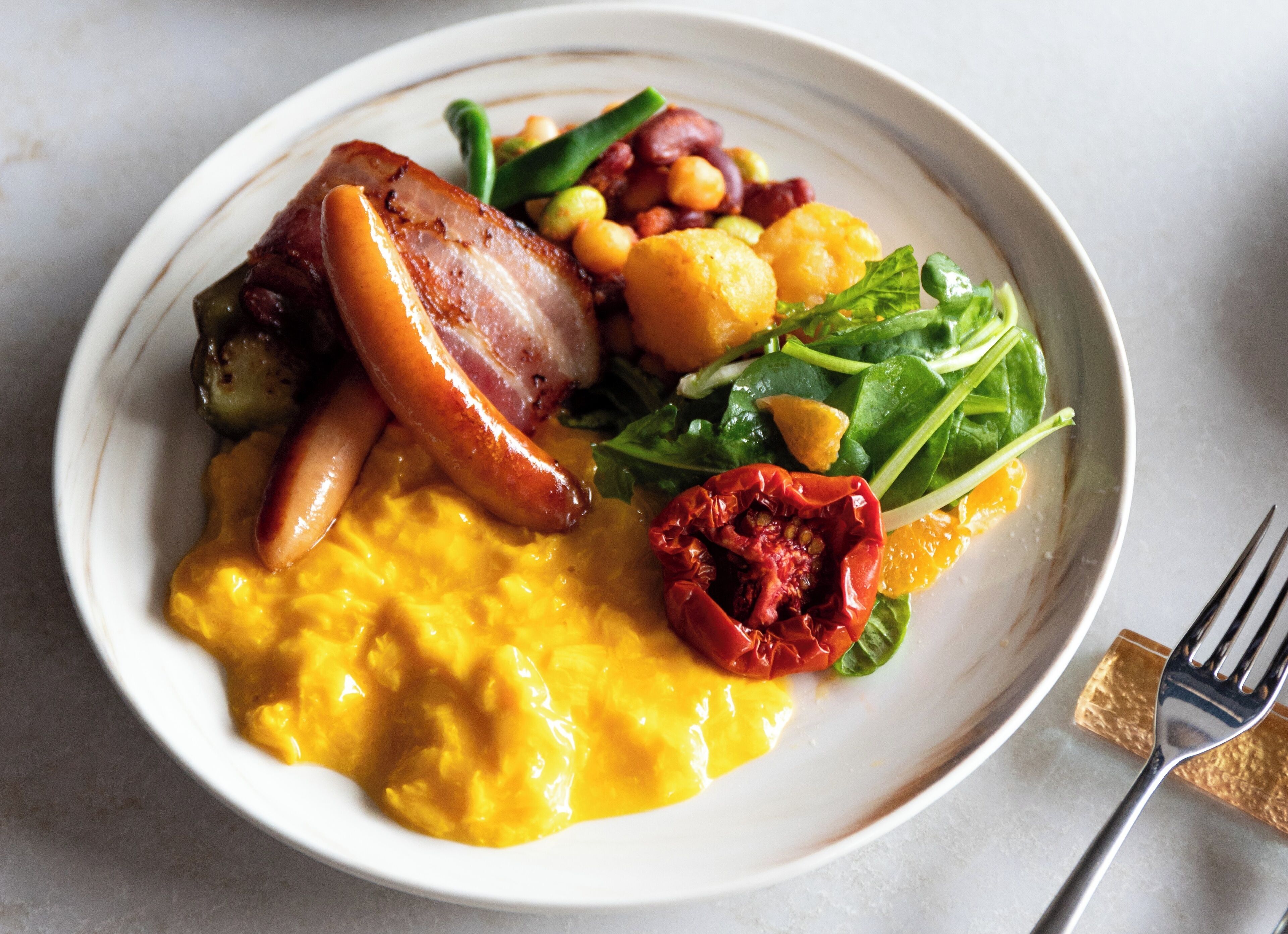 A plate of food with various items including a piece of meat, vegetables, and a yellow sauce.