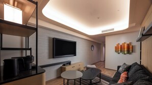 A modern living room with a flat-screen TV, a coffee machine, a small table, and a sofa with cushions. - Novotel Nara (Nara)