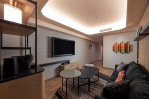 A modern living room with a flat-screen TV, a coffee machine, a small table, and a sofa with cushions. - Novotel Nara (Nara)