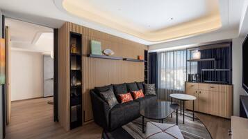 Una sala de estar moderna con un sofá, una mesita y una zona de cocina con ventana.