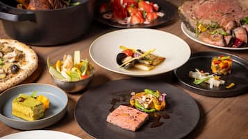 A variety of dishes on a wooden table, including a roasted turkey, steak, and several salads.