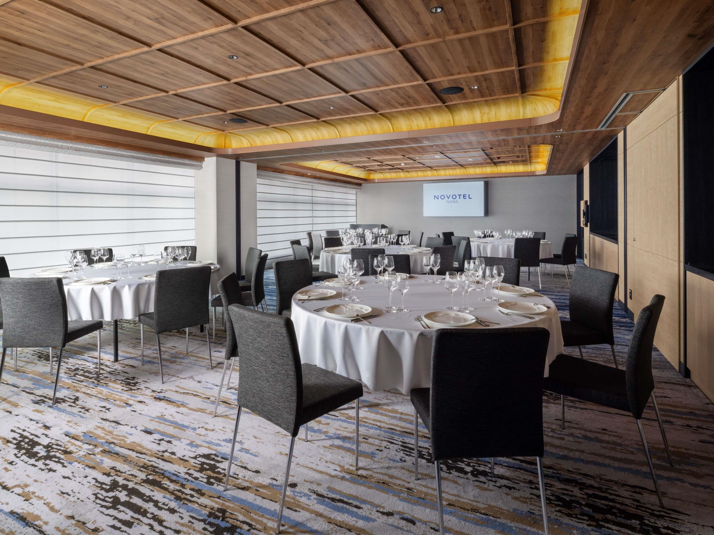 A conference room with round tables, chairs, and a wooden ceiling.