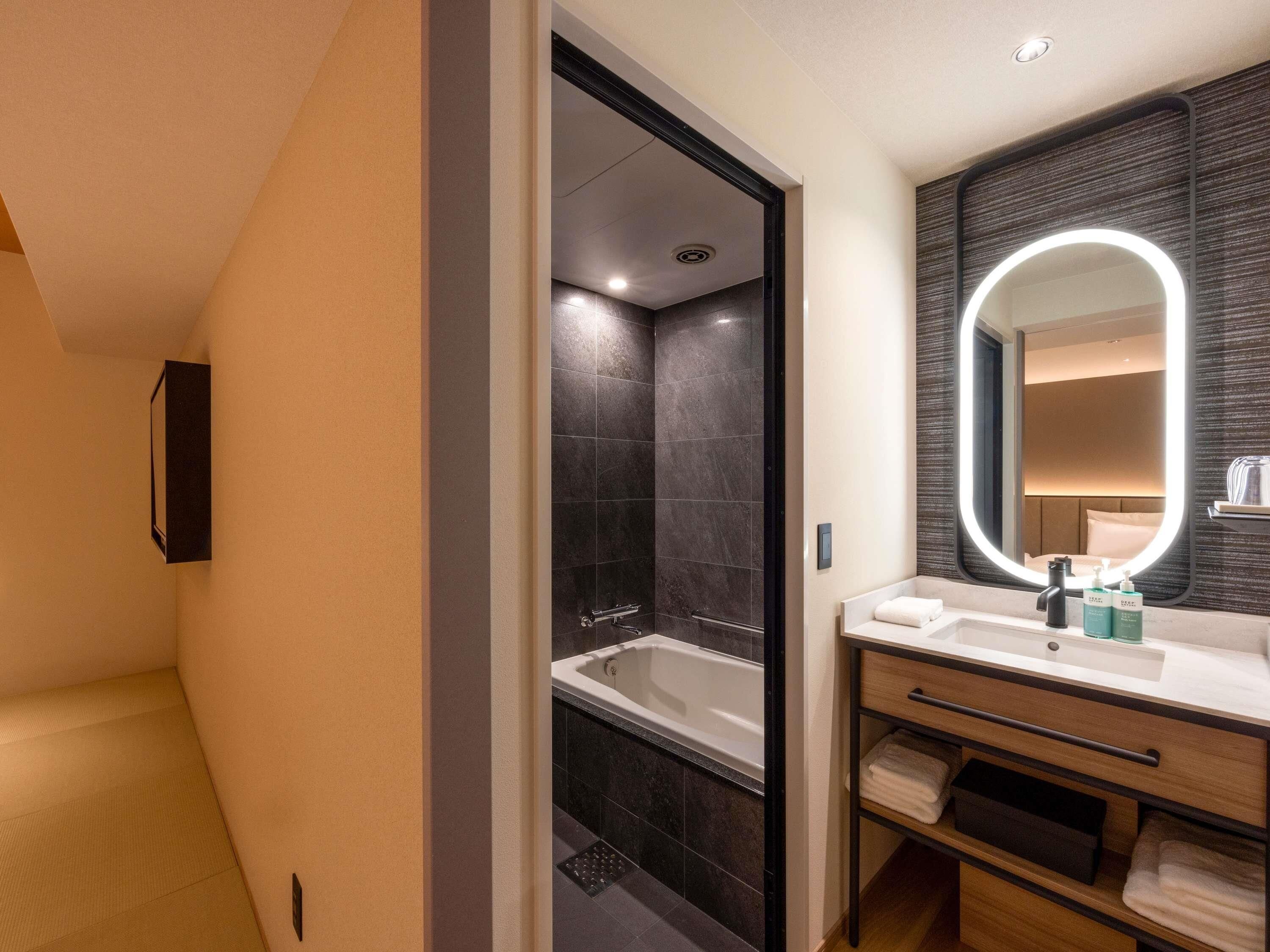 A modern bathroom with a bathtub, a vanity with a mirror, and a shower area.