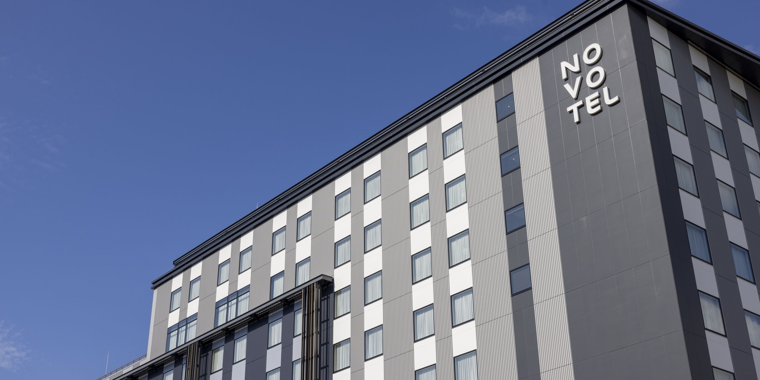 A modern hotel building with a prominent "NO VIVO" sign on the side.